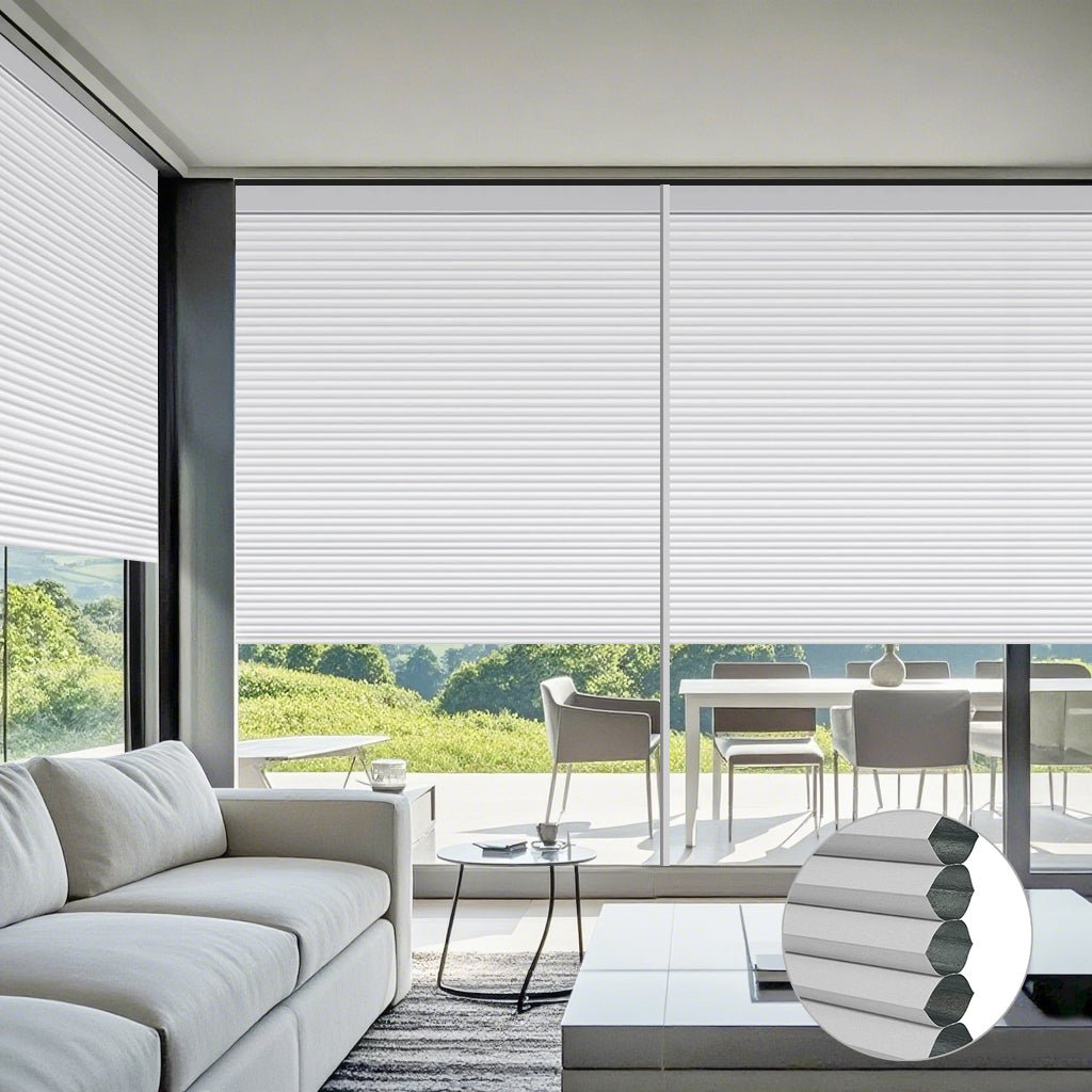 Motorized cellular shades in modern living room with white sofa, round side table, coffee cup, and large windows overlooking green landscape.